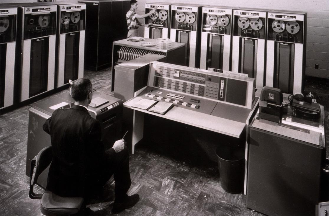 IBM 7090 photograph retained from the original source. Large shared computers made remote access valuable.